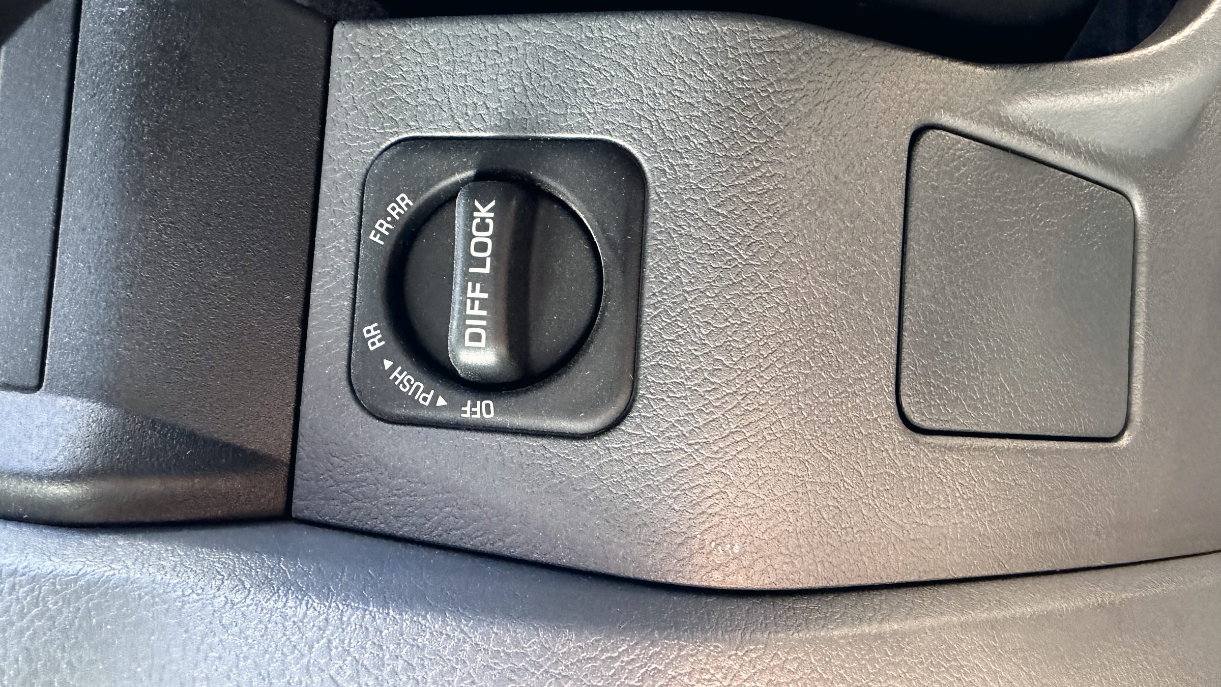 A dashboard-mounted diff-lock selector dial marked OFF, RR and FR-RR.