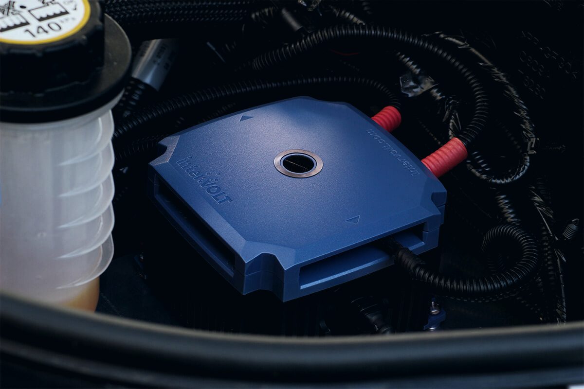 A blue DC-DC charger mounted in an engine bay with heavy cabling routed into it.